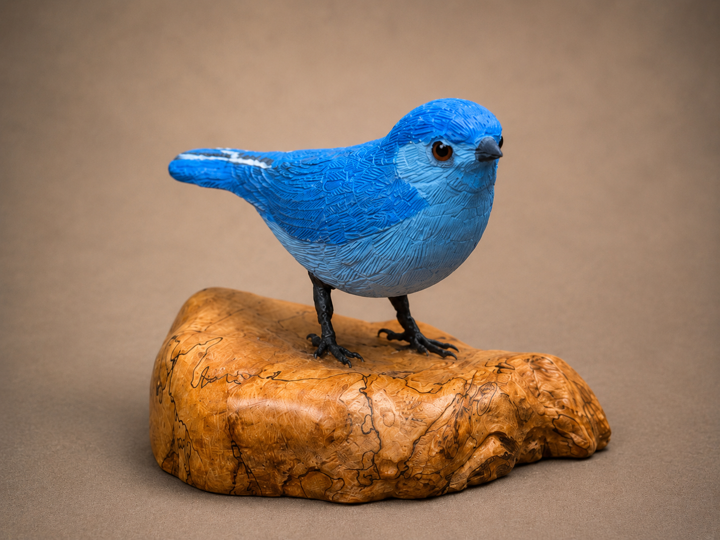 Mountain bluebird wildlife sculpture on a polished wooden base
