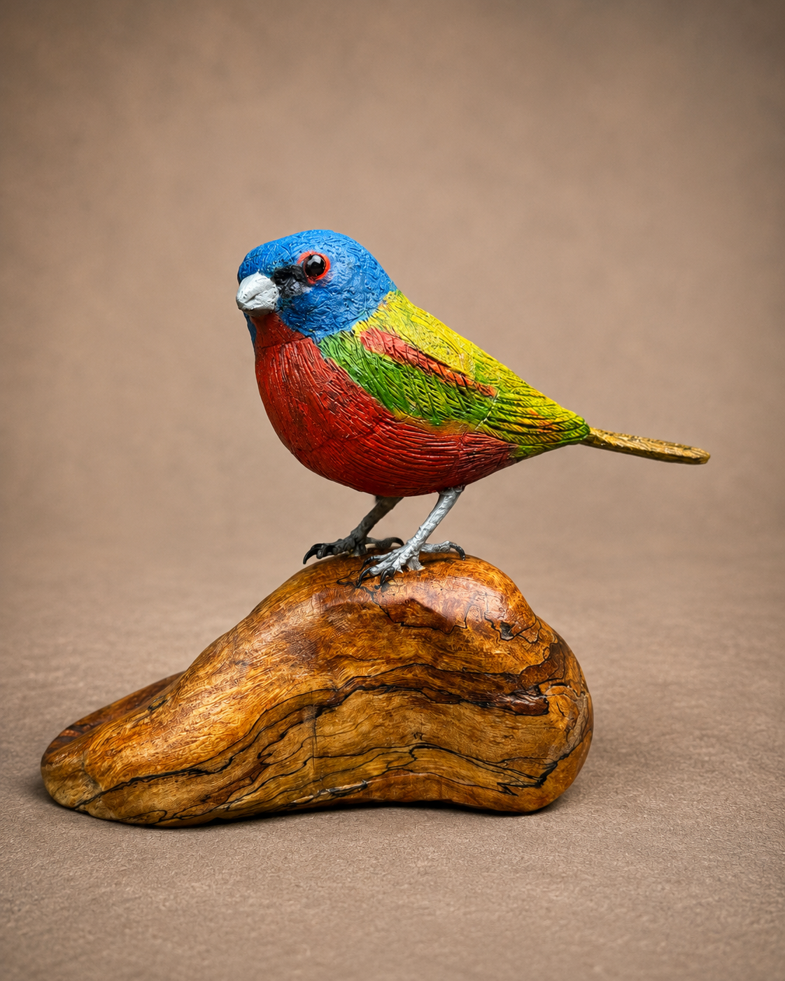 Painted bunting wildlife sculpture on a polished wooden base
