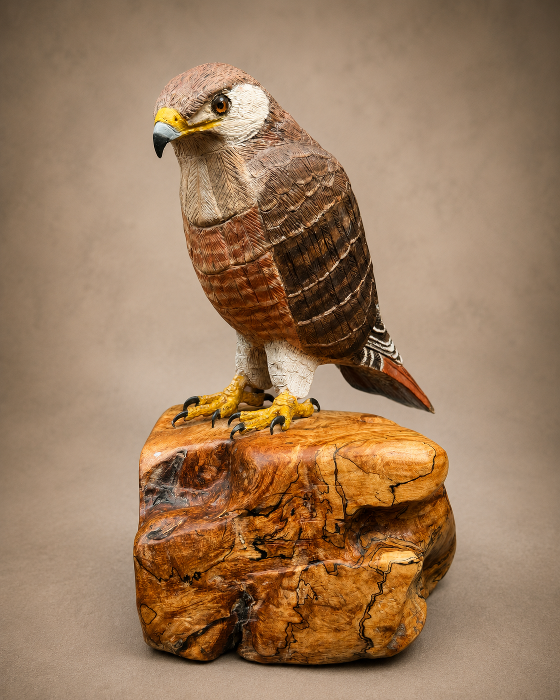 Red-tail hawk wildlife sculpture on a polished wooden base